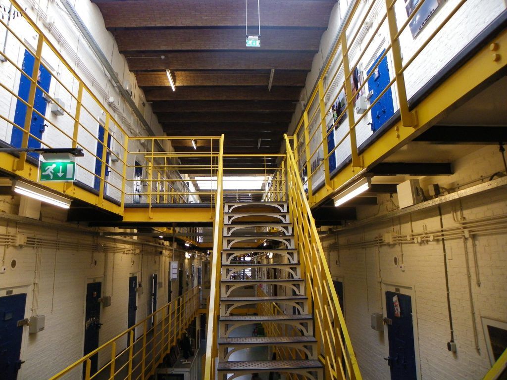 Image of stairs leading up and down to different cells within a corrections facility.