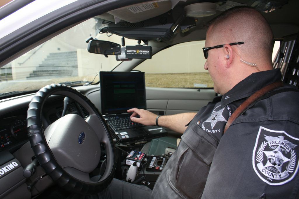 Image of an officer in his vehicle, typing on his mobile computer terminal.