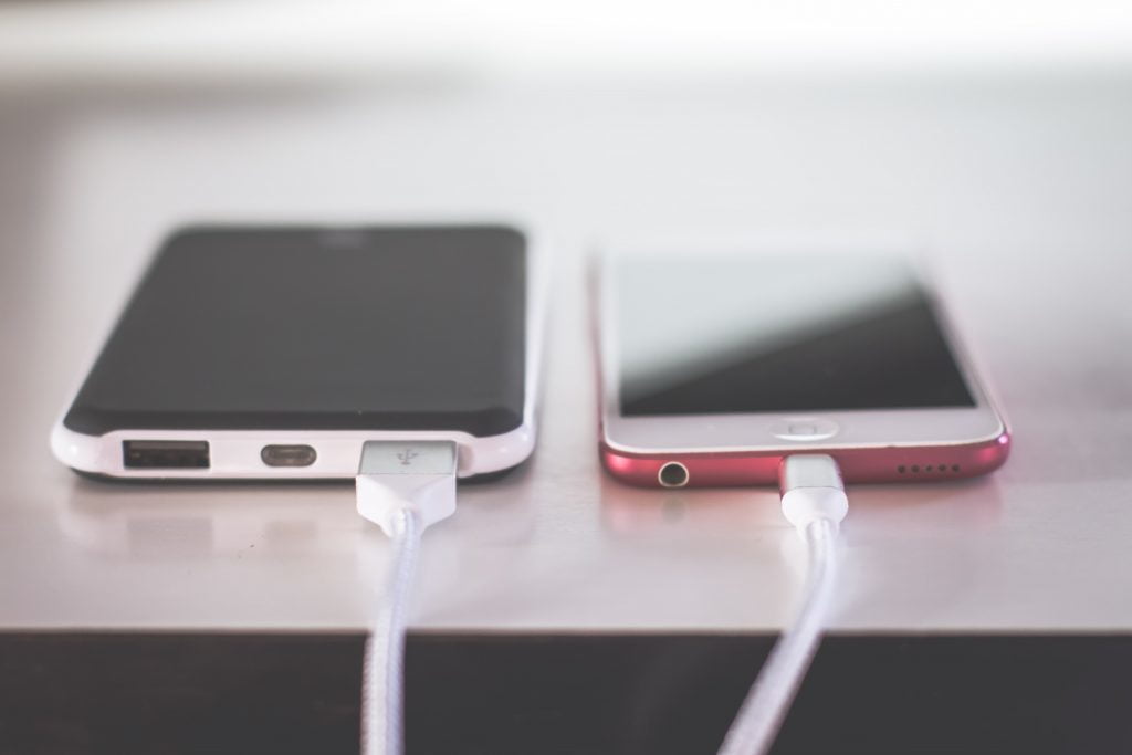 Image of an android phone and apple phone being charged next to each other.